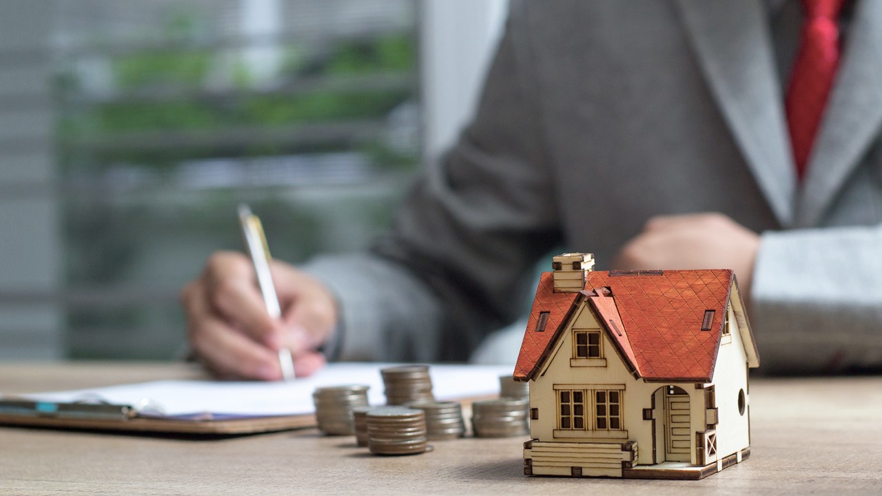 Business man signs contract behind a house of architectural model; image used for HSBC Singapore saving vs investing page.